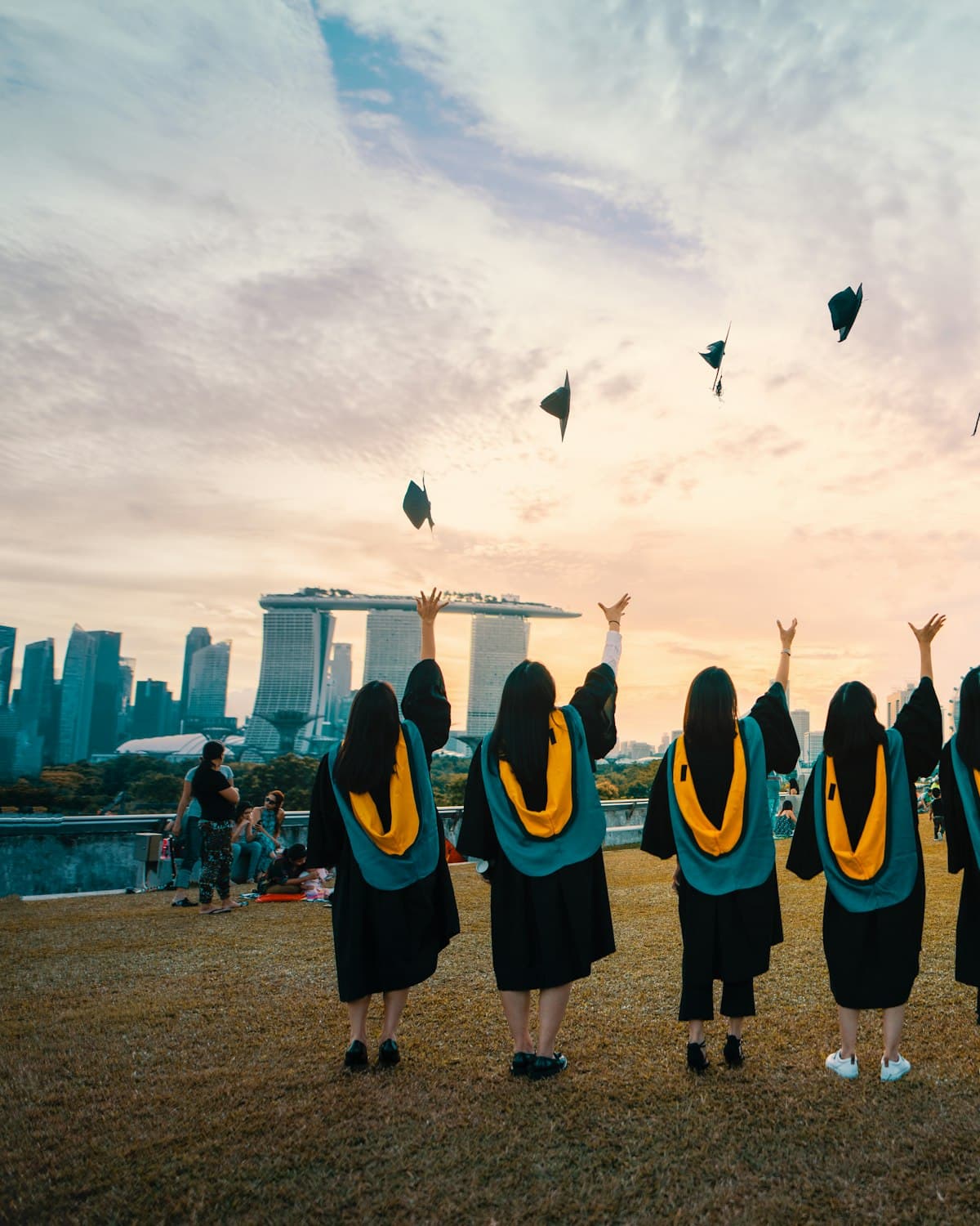 Students in graduation gowns tossing their caps at sunset